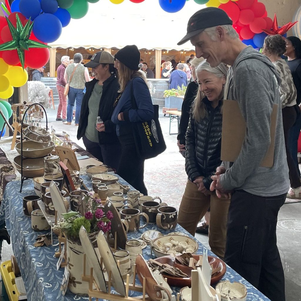 Couple browses Berkeley Art Club art market at Donkey and Goat Winery